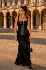 Corset gothique noir en similicuir à lacets porté avec une jupe longue satinée noire sur le parvis du Palais Garnier à Paris.