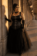 Femme grande taille portant un corset gothique noir à boucles métalliques avec jupe longue en tulle noir galerie valois à Paris à la golden hour.
