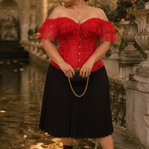 Photo éditoriale de mode d'une femme de 45 ans en grande taille 3XL portant un corset victorien rouge en jacquard avec manches en dentelle col Bardot, associé à une jupe midi plissée noire, photographiée à la Fontaine de Médicis à Paris à la golden hour du soir.