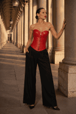 Corset similicuir rouge écarlate steampunk porté avec un pantalon noir élégant sous les Arcades de Valois du Palais-Royal à Paris.