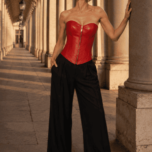 Corset similicuir rouge écarlate steampunk porté avec un pantalon noir élégant sous les Arcades de Valois du Palais-Royal à Paris.