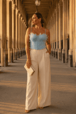 Femme portant un corset soutien-gorge bleu ciel à plumes avec pantalon crème élégant a la galerie de montpensier à Paris