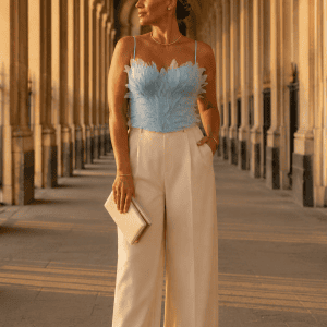 Femme portant un corset soutien-gorge bleu ciel à plumes avec pantalon crème élégant a la galerie de montpensier à Paris