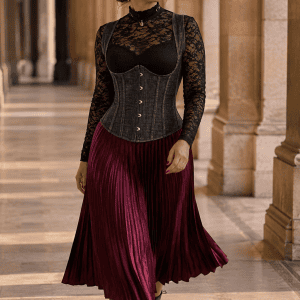 Corset underbust style jean noir délavé à bretelles porté avec un body en dentelle noire et une jupe midi plissée bordeaux à la Galerie de Montpensier au Palais Royal à Paris.