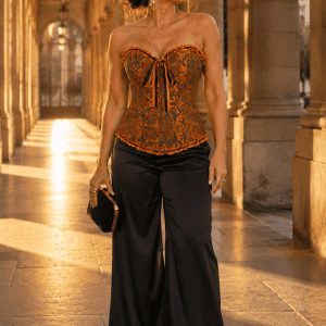 Femme de 45 ans portant un corset vintage orange doré style steampunk avec pantalon palazzo noir en satin a la galerie valois a Paris durant la golden hour du soir.