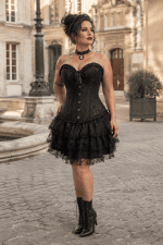 Robe corset bustier gothique romantique noire en brocart floral portée par une femme de 45 ans dans la cour du musée Carnavalet à Paris.