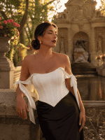 Femme de 40 ans portant un top corset satiné blanc style coquette avec jupe midi satinée noire a la fontaine de medicis golden hour dans un style éditorial haute couture.
