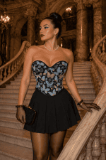 Corset bustier Renaissance en brocart noir à papillons bleus et dorés porté avec une jupe noire plissée