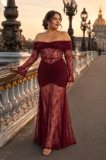 Femme portant une robe de soirée longue sirène bustier bordeaux, avec manches en dentelle florale et épaules dénudées, sur le pont Alexandre III à Paris.