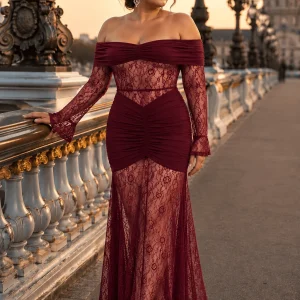 Femme portant une robe de soirée longue sirène bustier bordeaux, avec manches en dentelle florale et épaules dénudées, sur le pont Alexandre III à Paris.
